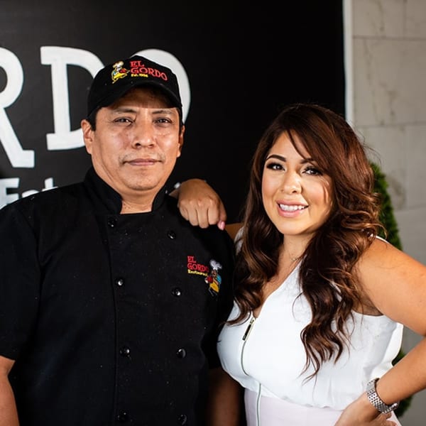 El Gordo Peruvian Eatery chef and woman smiling, with the restaurant logo visible.