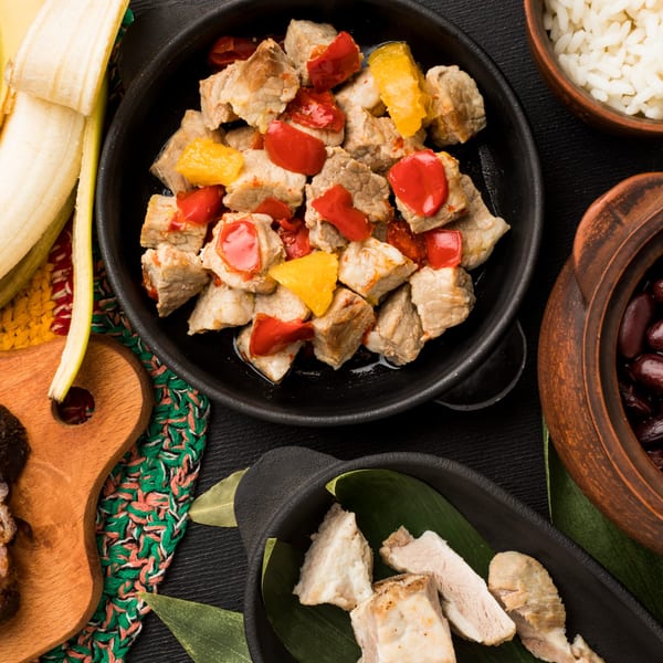 Cuban-style pork with red and yellow bell peppers, rice, black beans, and plantains.