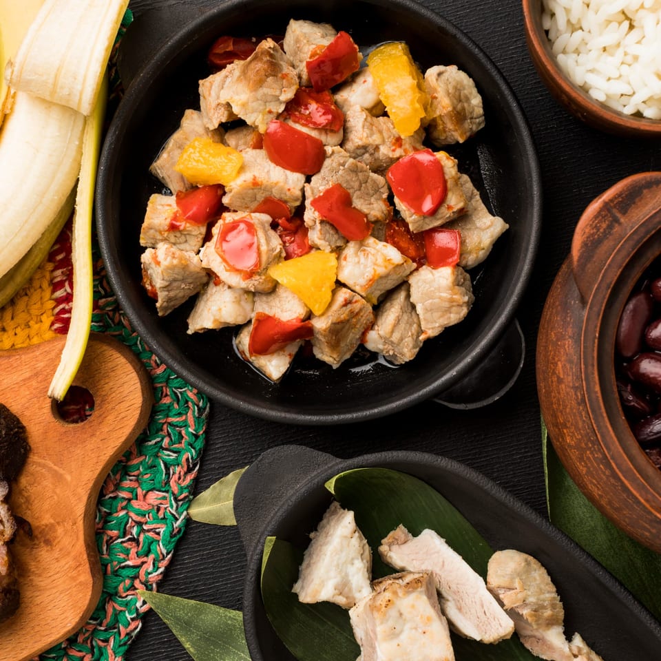 Cuban-style pork with red and yellow bell peppers, rice, black beans, and plantains.