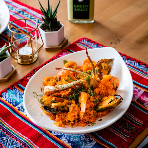 Peruvian Arroz con Mariscos, a seafood rice dish with crab, mussels, and shrimp, on a colorful woven placemat.