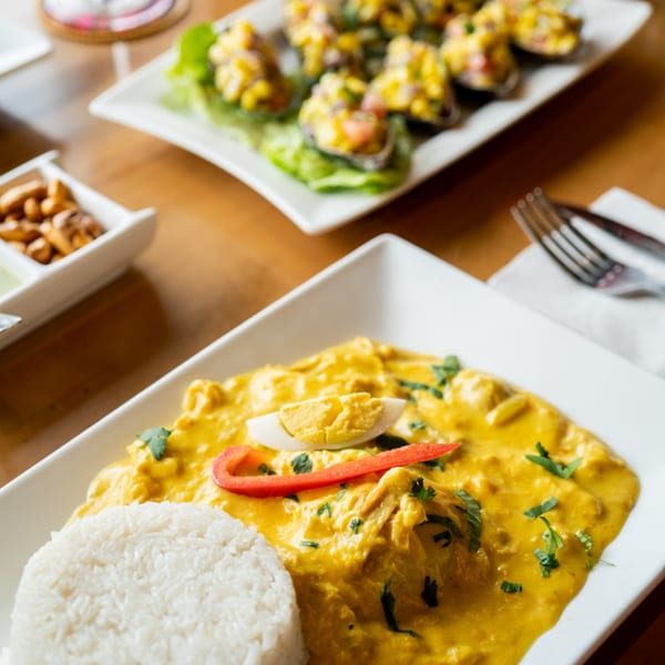 Peruvian Aji de Gallina with rice, egg, and red pepper, with mussels in the background.