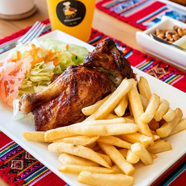Peruvian rotisserie chicken with crispy skin, golden french fries, and a fresh side salad.