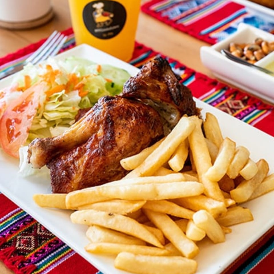 Peruvian rotisserie chicken with crispy skin, golden french fries, and a fresh side salad.